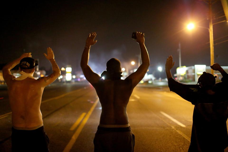 Demonstrators raise their arms and chant, "Hands up, Don't Shoot", as police clear them from the street as they protest the shooting death of Michael Brown on Aug. 17, 2014, in Ferguson, Missouri.