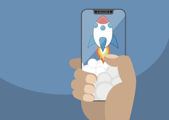 A hand holding a smartphone displaying a cartoon rocket ship taking off.