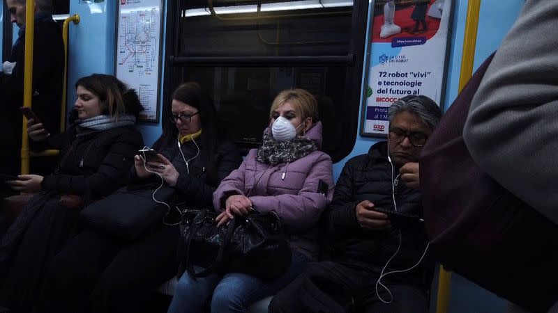 A woman wearing a protective mask takes the metro during rush hour in Milan