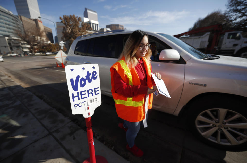 Election judge Amanda Vigil collects a ballot from a motorist at the drive-through site of the Denver Elections Division outside the City/County Building early Tuesday, Nov. 5, 2019, in Denver. (AP Photo/David Zalubowski)