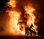 Aug 23, 2020; Kenosha, WI, USA; A man on a bike rides past a city truck on fire outside the Kenosha County Courthouse in Kenosha on Sunday, Aug. 23, 2020. Kenosha police shot a man Sunday evening, setting off unrest in the city after a video appeared to show the officer firing several shots at close range into the man's back. Mandatory Credit: Mike De Sisti/Milwaukee Journal Sentinel via USA TODAY NETWORK/Sipa USA