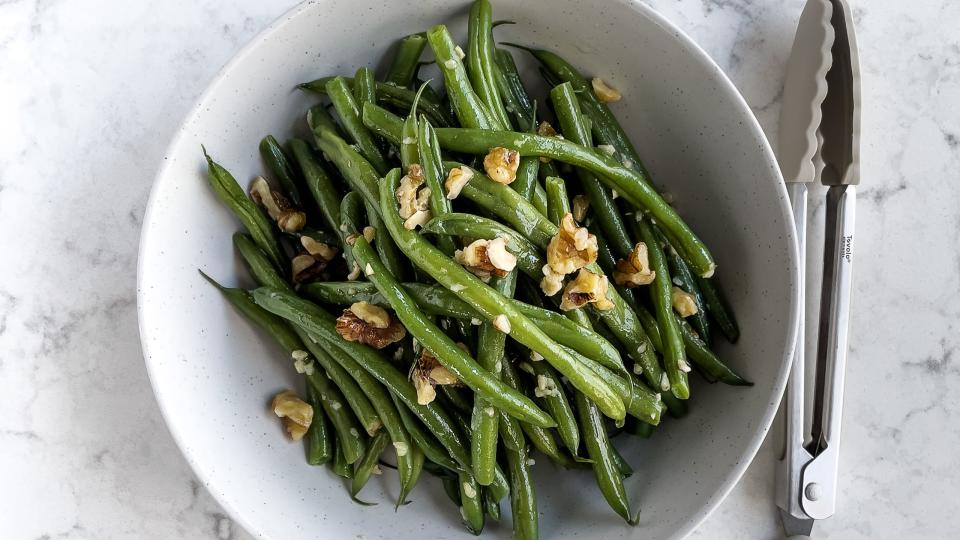 bowl of green beans salad on white, marble background