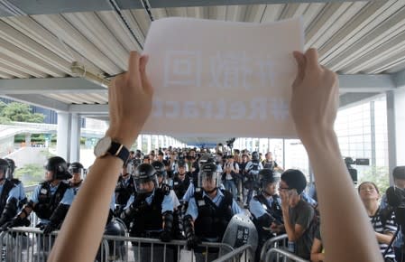 Police block a footbridge leading to the Legislative Council as a protester holds a sign in Hong Kong