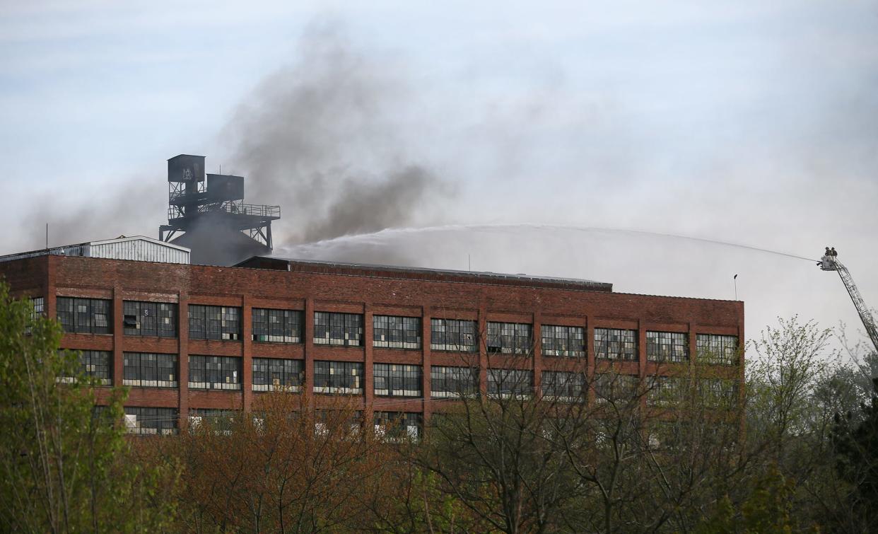 Akron firefighters spray water in a courtyard area on Thursday as they battle a fire in an abandoned factory at the corner of River and Johnston streets in Akron.