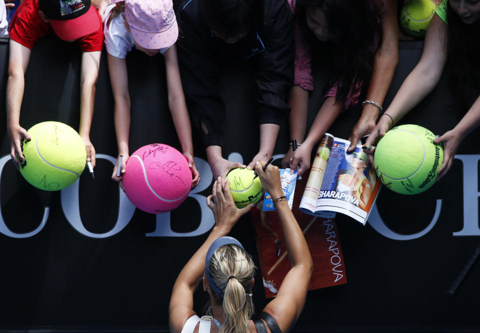 Maria Sharapova of Russia signs autographs after defeating compatriot Olga Puchkova in their women's singles match at the Australian Open tennis tournament in Melbourne, January 14, 2013. REUTERS/David Gray (AUSTRALIA - Tags: SPORT TENNIS TPX IMAGES OF THE DAY)