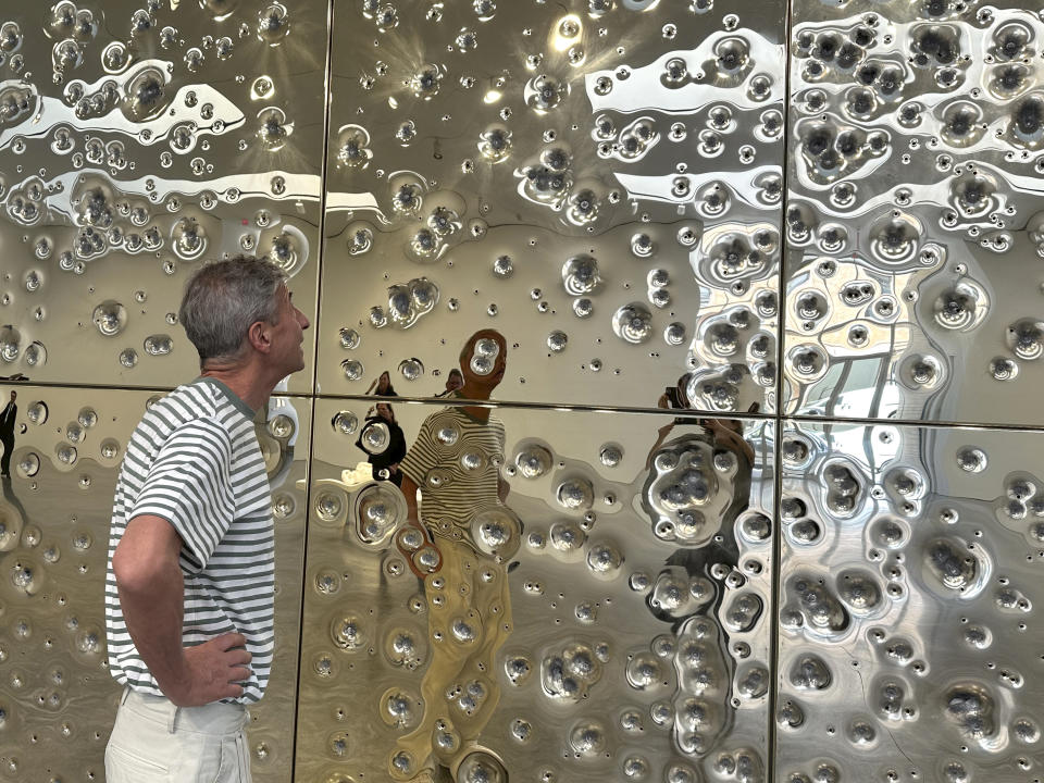 Italian artist Maurizio Cattelan inspects his installation, "Sunday," at Gagosian gallery on May 1, 2024, in New York. The installation consists of 64 panels plated with 24-karat gold and pockmarked by gunfire. (AP Photo/Jocelyn Noveck)