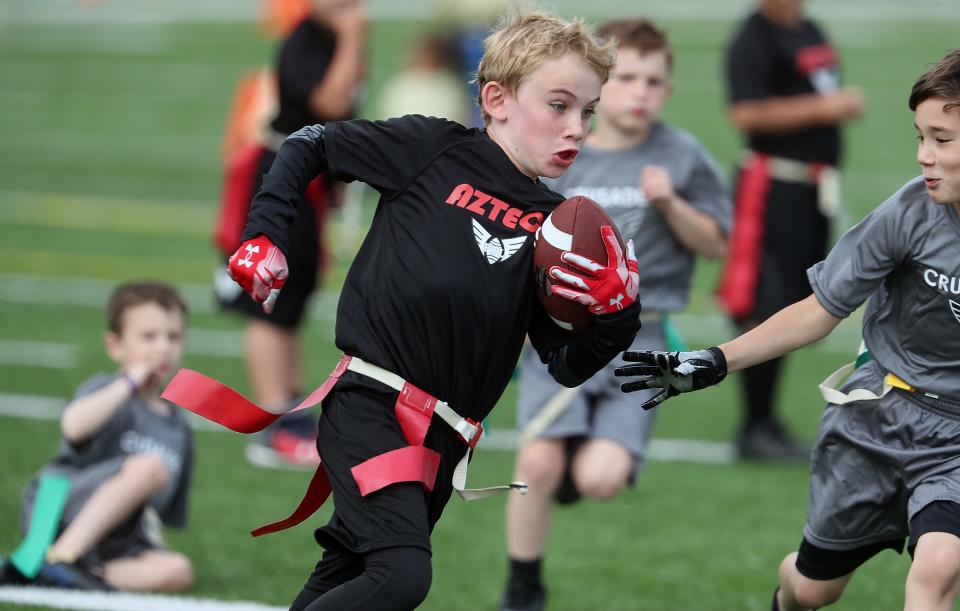 An Aztecs player dodges the flag grabs of Crusaders offensive players and heads for the goal line at Central Kitsap's Cougar Field on Thursday, June 23, 2022.