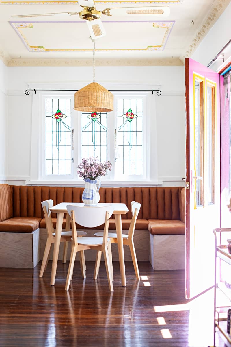 A breakfast nook surrounds a dining table with three chairs in a white kitchen with decorative wall dressings.