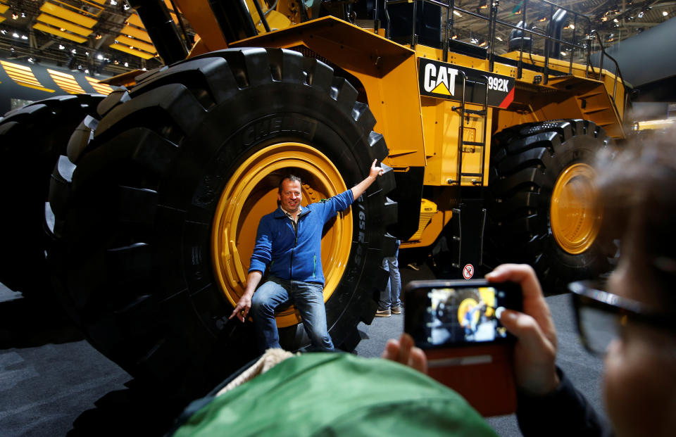 A man poses in a wheel of a Caterpillar excavator at the 'Bauma' Trade Fair for Construction Machinery, Building Material Machines, Mining Machines, Construction Vehicles and Construction Equipment in Munich, Germany, April 8, 2019. REUTERS/Michaela Rehle