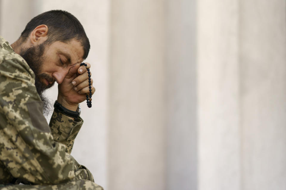 A Ukrainian serviceman prays during a service at St. Michael's Ukrainian Orthodox Church of the Moscow Patriarchate on Savior of the Honey Feast Day in Pokrovsk, Donetsk region, eastern Ukraine, Sunday, Aug. 14, 2022. (AP Photo/David Goldman)