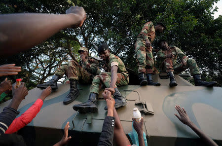 FILE PHOTO: Zimbabweans celebrate with soldiers after President Robert Mugabe resigns in Harare, Zimbabwe November 21, 2017. REUTERS/Mike Hutchings/File Photo