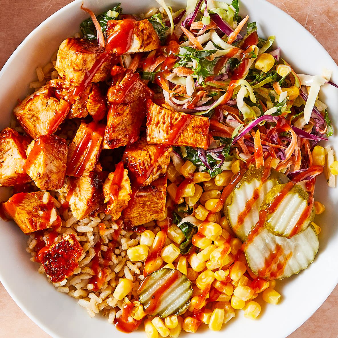 Barbecue chicken in a grain bowl with corn, pickles and coleslaw