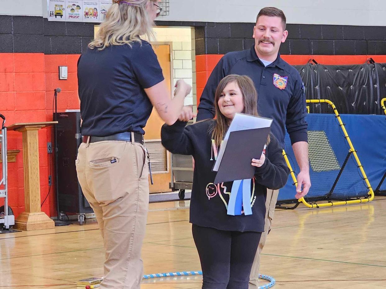 Gorrell third grader Eliana DeMando, middle, fist bumps Ohio's Division of State Fire Marshal safety educator Ashley Terry as fire safety educator Kyle Wobler looks on. Eliana was honored earlier this week as one of six winners in the agency's poster contest.