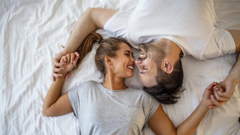 Couple smiling in bed (Getty Images)