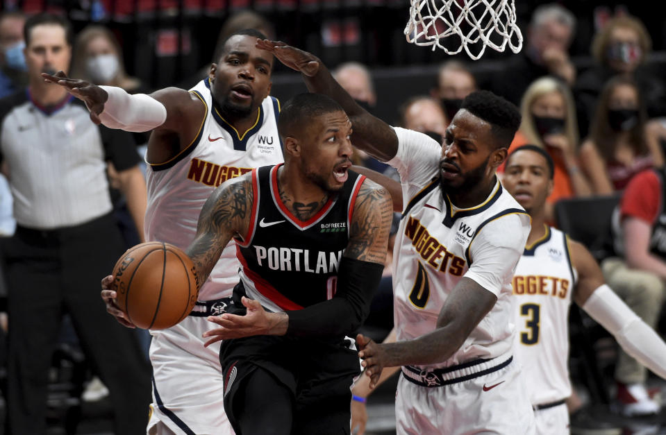 Portland Trail Blazers guard Damian Lillard, center, passes the ball as Denver Nuggets forward Paul Millsap, left and forward JaMychal Green, right, defend during the second half of Game 4 of an NBA basketball first-round playoff series in Portland, Ore., Saturday, May 29, 2021. The Blazers won 1115-95. (AP Photo/Steve Dykes)