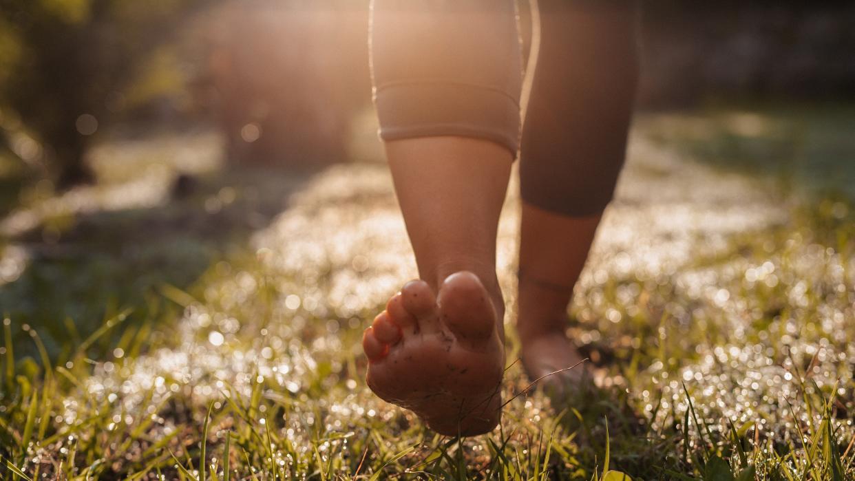  Young woman doing walk-meditation in her garden . 