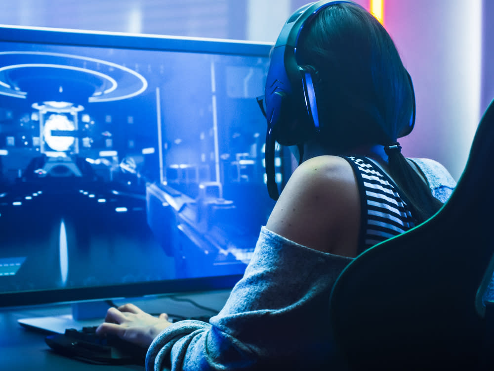 Eine junge Dame vor ihrem Gaming-Setup (Symbolbild). (Bild: Gorodenkoff/Shutterstock.com)