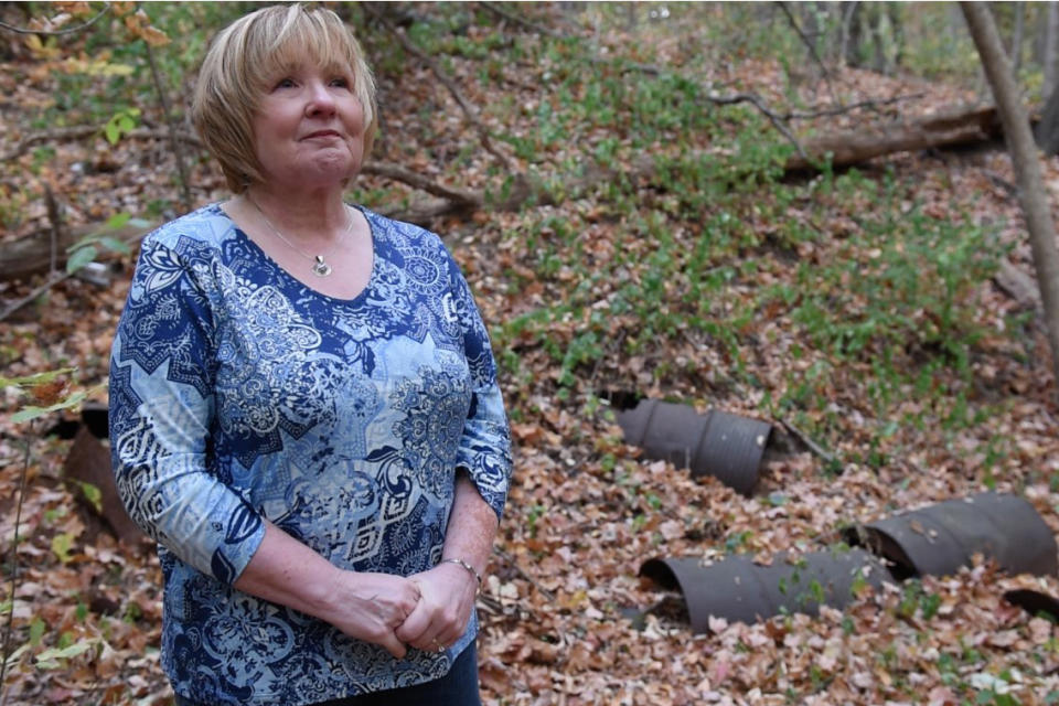 In this photo taken in September 2017, Sandy Wynn-Stelt, of Belmont, Mich., stands in a wooded area near her home where industrial wastes containing PFAS chemicals were dumped for many years. High levels of the toxic compounds later were detected in drinking water from her well. While estimates vary, studies say roughly 53 million U.S. residents rely on private wells. While many provide safe water, experts say some are vulnerable to contamination from bacteria or other impurities from floodwaters or from groundwater tainted with PFAS or other pollutants. (Nic Antaya/The Grand Rapids Press via AP)