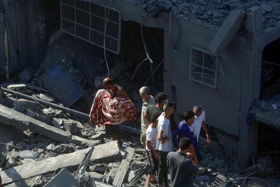 Palestinians carry a body found under the rubble of a destroyed building following an Israeli airstrike in Bureij refugee camp, Gaza Strip (AP)