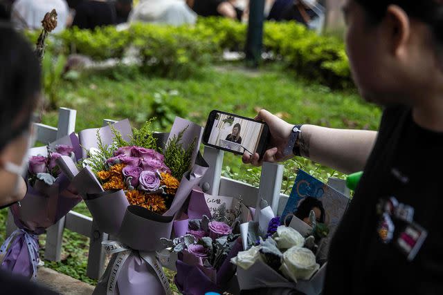 <p>Getty Images</p> Fans watch the funeral on their phones on July 31, 2023