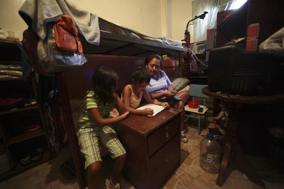 In this Sept. 27, 2012 photo, Maribel Rodriguez, right, sits with her daughters as they do their homework in the room where they live that was once a school but is now a government provided shelter for families who have lost their homes due to flooding, in Caracas, Venezuela. Fear of every stripe, like the loss of government housing like this one, permeates the intensely polarized election campaign, with many votes to be decided based not on the candidates' promises but rather on what worries people most. Chavez has continuously warning of chaos and the dismantling of the generous welfare state he built if he is voted out of office in the Oct. 7 vote. (AP Photo/Fernando Llano)