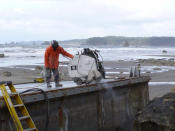 A worker uses a walk-behind saw to cut the top of the dock.