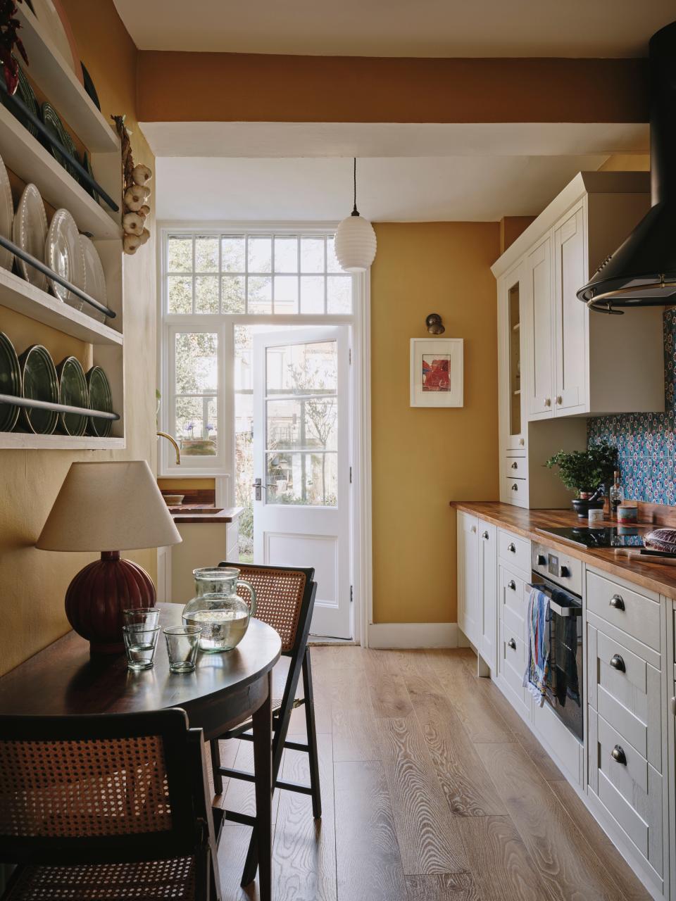 “This was a huge transformation,” James says of the kitchen. “The room is north-facing, so finding a color that would be warm all through the year was key.” He channeled his grandmother’s kitchen in Greece with retro wall tiles, a cottage-style plate rack, and an Old School Electric Beehive pendant from Holloways of Ludlow. The print is by Greek artist Alekos Fassianos.