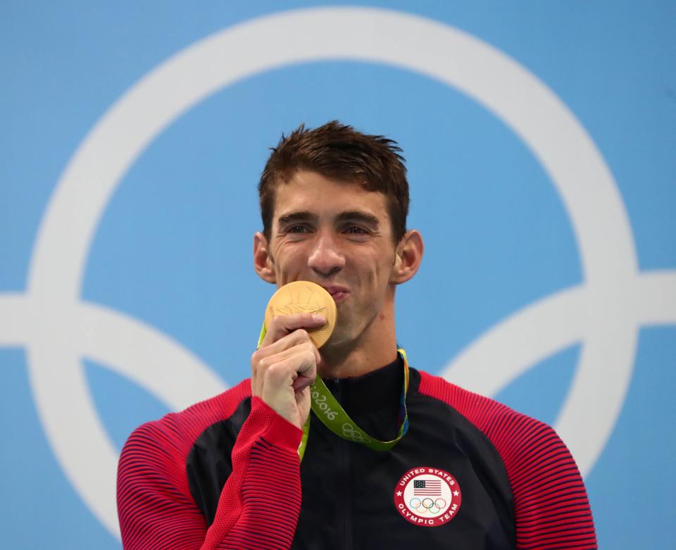 Michael Phelps kisses his gold medal after swimming in the men's 200-meter individual medley at the 2016 Rio Olympics.