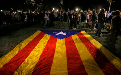 A pro-independence Catalan flag lies on the grass, as demonstrators gather outside the Catalonian Parliament - Credit: AP