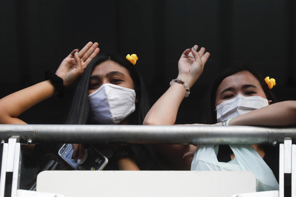 Two women flash three-finger protest gestures while wearing headbands adorned with yellow ducks, which have become a good-humored symbol of resistance during anti-government rallies, Friday, Nov. 27, 2020 in Bangkok, Thailand. Pro-democracy demonstrators are continuing their protests calling for the government to step down and reforms to the constitution and the monarchy, despite legal charges being filed against them and the possibility of violence from their opponents or a military crackdown. (AP Photo/Wason Wanichakorn)