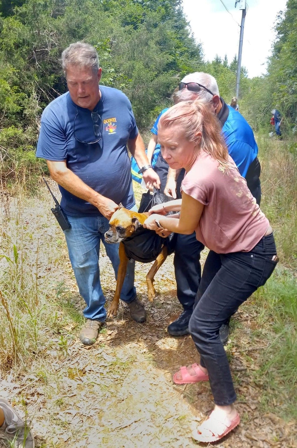 Oconee County Medical First Responders Dennis Luckey and Susan Weldon help carry a dog after it was rescued from an abandoned well.