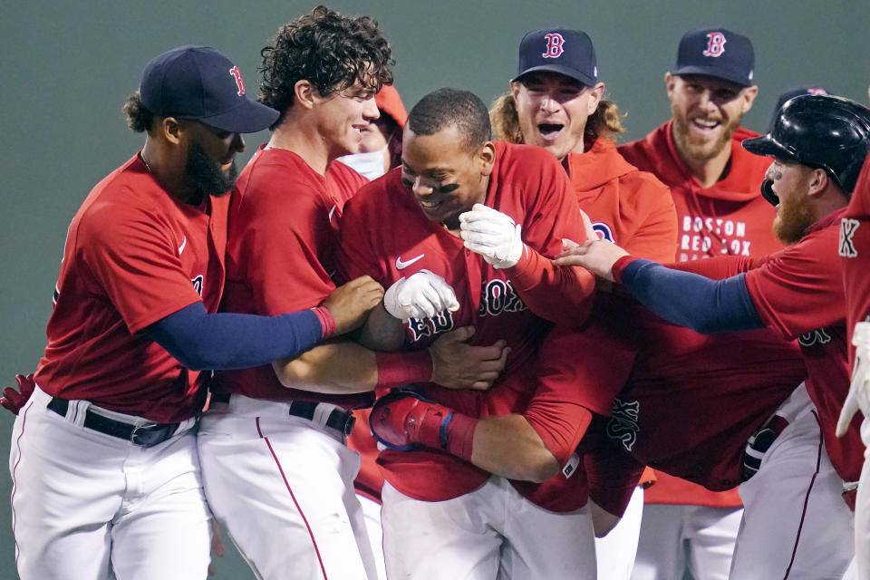 Boston Red Sox's Rafael Devers, center, is surrounded by teammates while celebrating his winning RBI-single in the bottom of the ninth inning of a baseball game against the Toronto Blue Jays at Fenway Park, Monday, June 14, 2021, in Boston. (AP Photo/Charles Krupa)