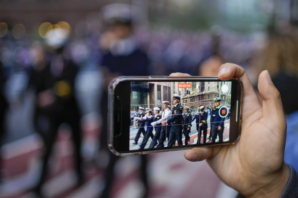 A member of the crowd films the Anzac Day parade in central the business district of Sydney, Australia, Thursday, April 25, 2024. (AP Photo/Mark Baker)