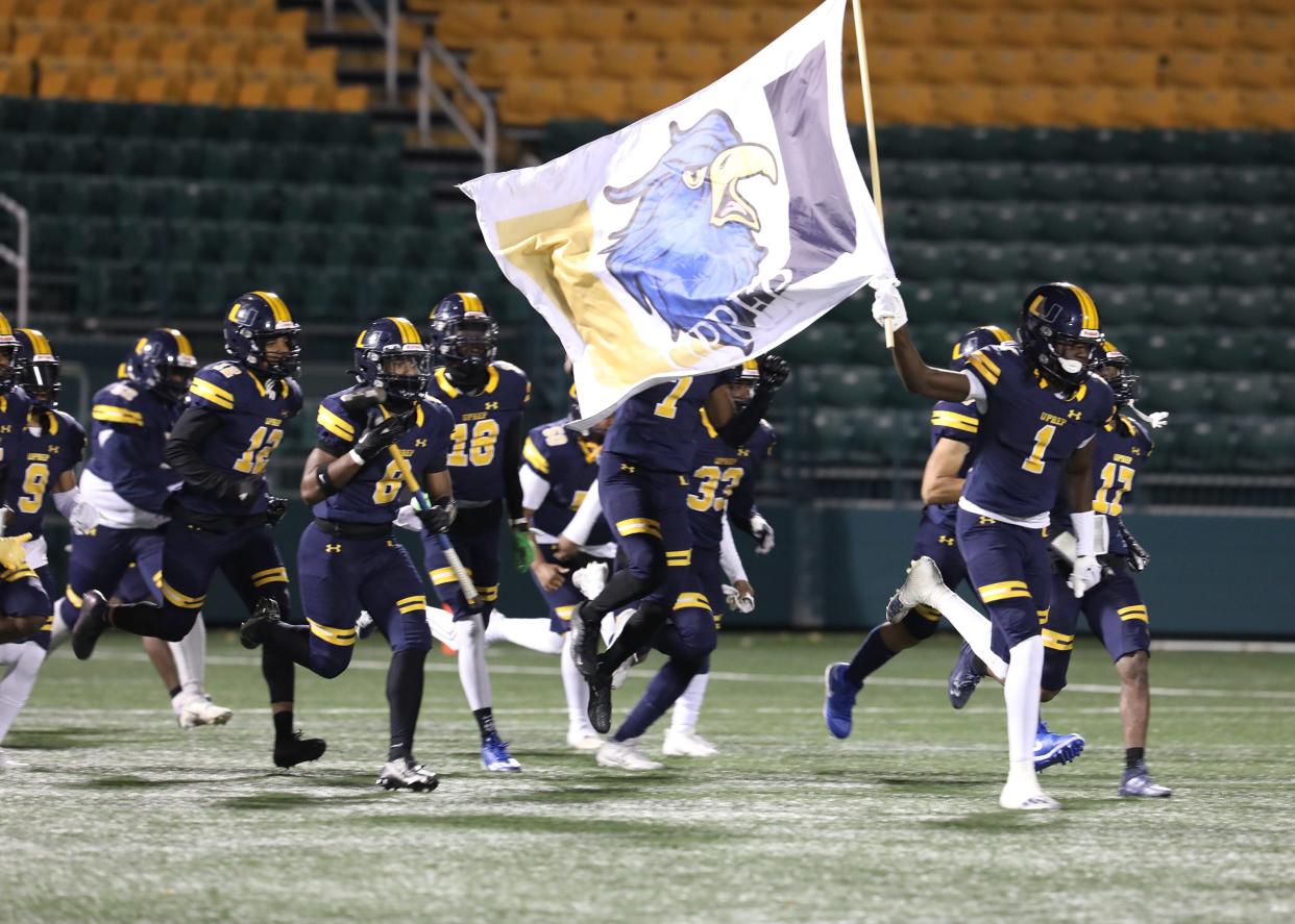 UPrep's Tyrell Simmons leads his teammates onto center field carrying the school flag while teammate Taivon Wilson carries the sledgehammer.