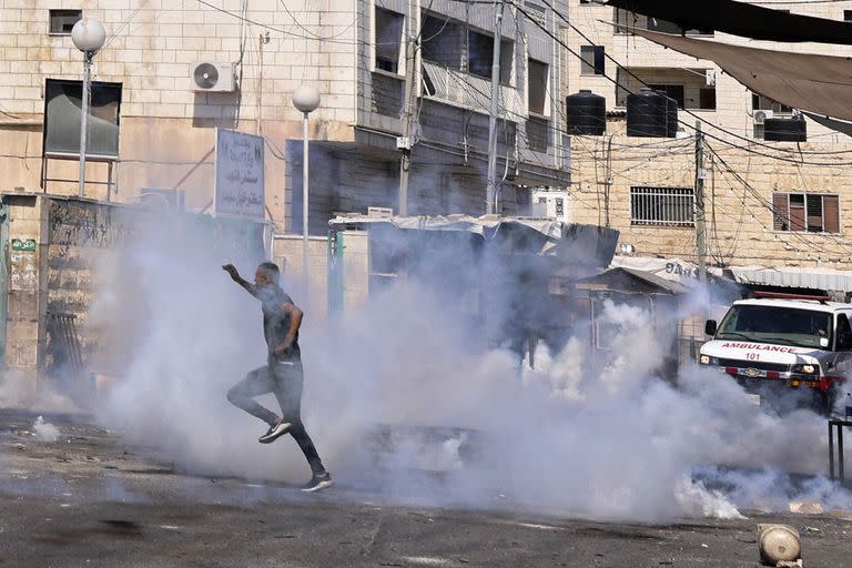 Una persona escapa en medio disparos de gases lacrimógeno. (Photo by Jaafar ASHTIYEH / AFP)