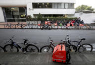 Bicycle couriers wait for messages from the Rappi application to take orders to clients in Bogota, Colombia, Monday, July 8, 2019. Rappi, like similar companies, has also come under criticism for its modern-day labor practices, which reflect some of the shortcomings of the gig economy. (AP Photo/Fernando Vergara)