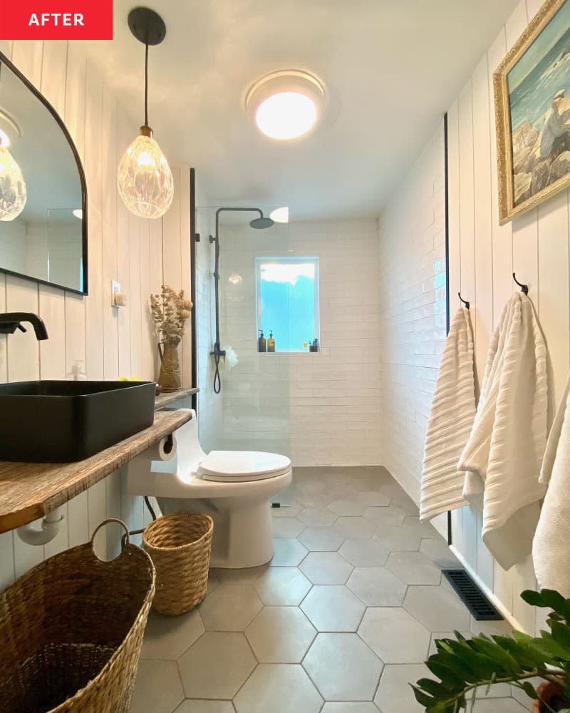 Open, airy bathroom with grey hexagonal, glass walk in shower and black sink.