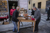 Stall-holders set up a table with antiques in the Rastro flea market in Madrid, Spain, Sunday, Nov. 22, 2020. Madrid's ancient and emblematic Rastro flea market reopened Sunday after a contentious eight-month closure because of the COVID-19 pandemic that has walloped the Spanish capital. (AP Photo/Paul White)