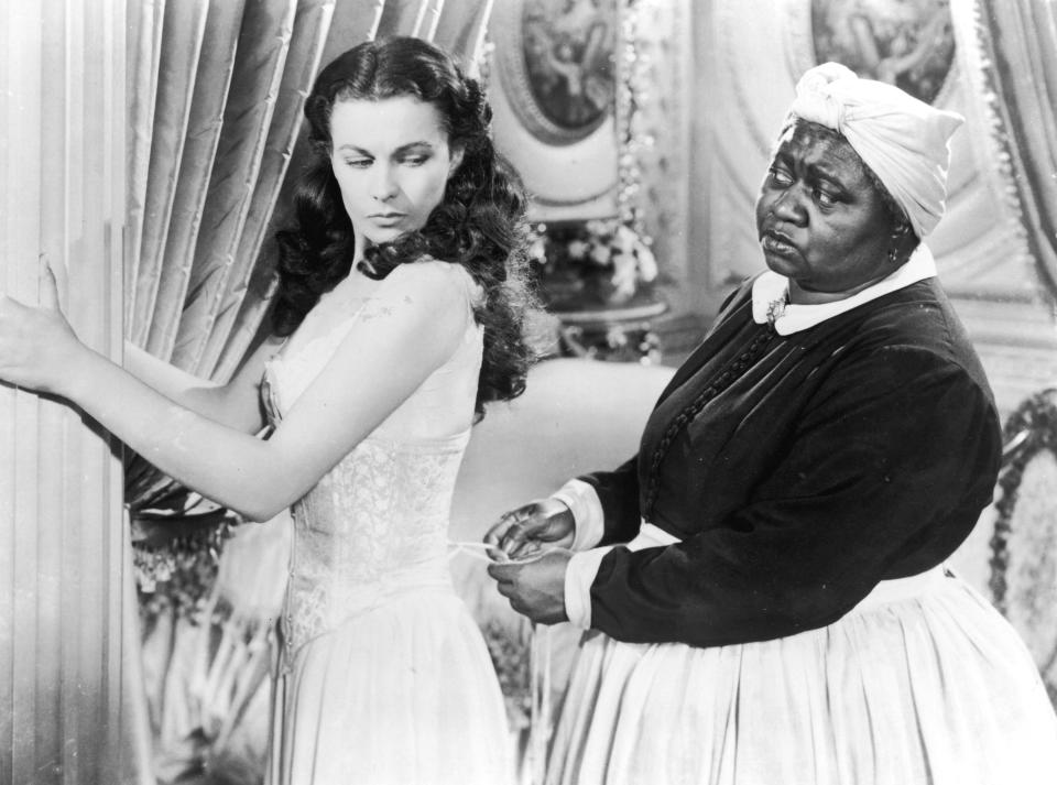Vivien Leigh holds onto a pillar as Hattie McDaniel tightens her corset in "Gone with the Wind"