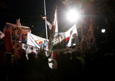 Supporters of South Korea's ousted leader Park Geun-hye wave national flag and pictures of Park as they wait for her arrival outside her private home in Seoul, South Korea, March 12, 2017. REUTERS/Kim Kyung-Hoon