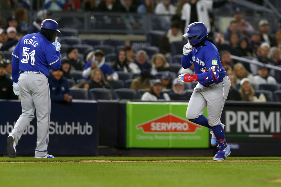 Toronto Blue Jays third base coach Carlos Febles, left, and first baseman Vladimir Guerrero Jr., right, both hold a finger to their mouths as Guerrero heads home after hitting a solo home run in the seventh inning during the baseball game against the New York Yankees Saturday, April 6, 2024, in New York. (AP Photo/John Munson)