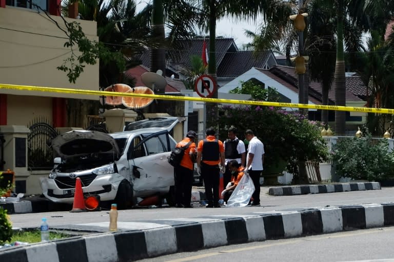 Indonesian policemen examine a car used by attackers during an assault on a police headquarters on the island of Sumatra that left one officer dead and two wounded