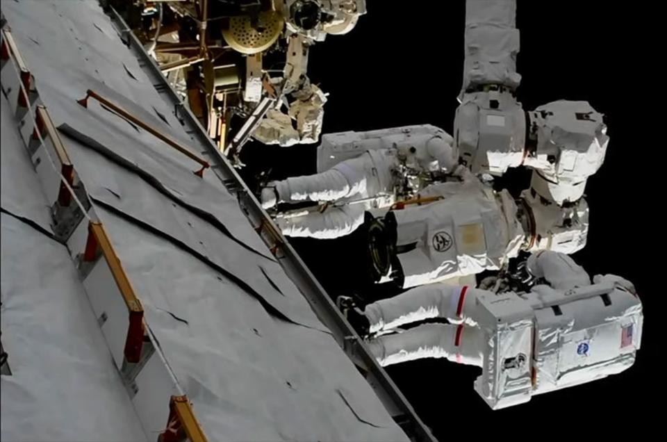 NASA astronauts Randy Bresnik (foreground, with red stripes) and Mark Vande Hei work to install a replacement latching end effector, or hand, on the Canadarm2 robotic arm outside of the International Space Station during a spacewalk on Oct. 5, 2017 <cite>NASA TV via collectSPACE.com</cite>