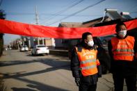 Village committee members wearing face masks and vests stand at the entrance of a community to prevent outsiders from entering, as the country is hit by an outbreak of the new coronavirus, in Tianjiaying village, outskirts of Beijing