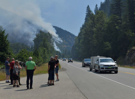 Tourists from Denmark stop to photograph one of several wildifres burning near Little Fort, British Columbia, Canada July 9, 2017. REUTERS/Dennis Owen