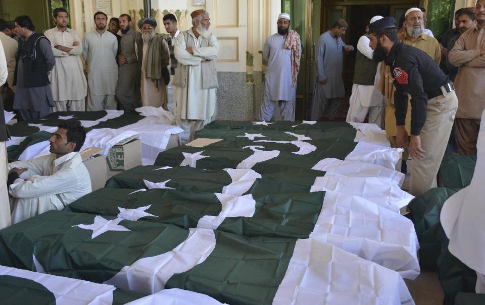 FILE -- In this Oct. 25, 2016 file photo, people wait to carry the bodies of their family members who died in an attack on the Police Training Academy, in Quetta, Pakistan. Two Pakistani research groups have noted a significant drop in militant violence in the country last year but say that for the trend to continue, authorities need to fight sectarian and anti-Indian extremists based in the most populous Punjab province. (AP Photo/Arshad Butt)