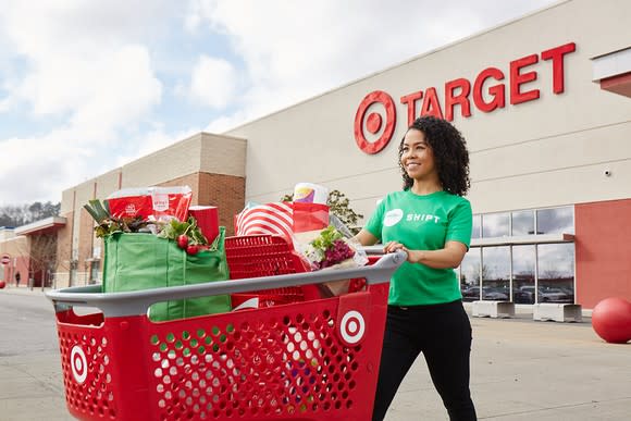 A woman wearing a Shipt shirt pushing a target shopping car outside of a store.