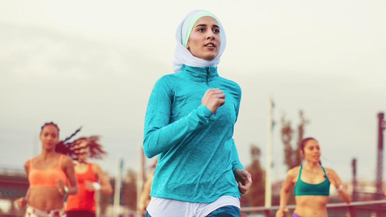 a woman in focus with four women behind her out of focus, all running — presumably running a half marathon