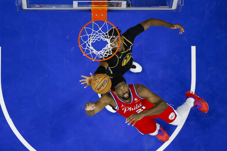 Philadelphia 76ers' Joel Embiid, right, shoots while being guarded by Golden State Warriors' Kevon Looney, left, during the first half of an NBA basketball game, Saturday, Dec. 11, 2021, in Philadelphia. (AP Photo/Chris Szagola)