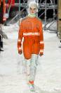 <p>A model wears a cropped orange safety jacket and trousers with reflective panels, a balaclava, and thigh-high white protective boots at the Calvin Klein fall 2018 show. (Photo: Getty Images) </p>